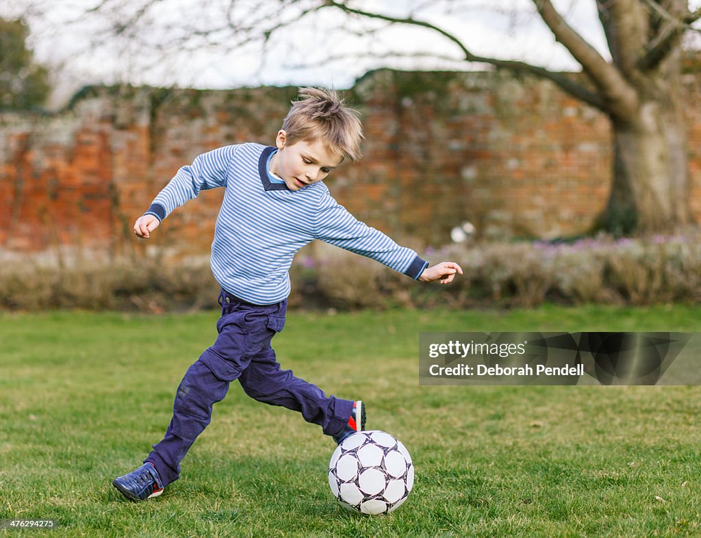 Young boy playing football in the garden