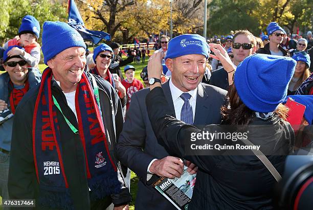 Tony Abbott has his beanie adjusted as he joins Neale Daniher to walk to the MCG ahead of the round 10 AFL match between the Melbourne Demons and the...