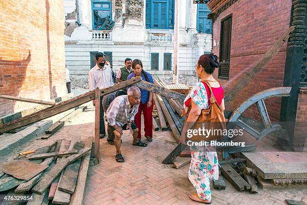 People walk under a makeshift brace structure used to hold up damaged buildings at Durbar Square in Lalitpur, Kathmandu Valley, Nepal, on Thursday,...