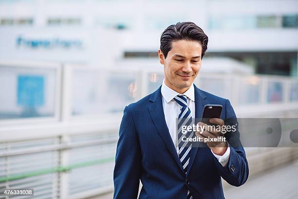 japanese businessman in tokyo with smart phone texting outdoors - men's formalwear stock pictures, royalty-free photos & images