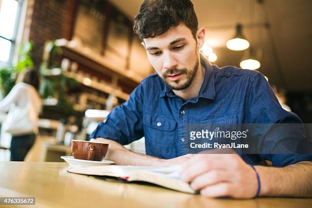 man reading book in coffee shop - bible stockfoto's en -beelden