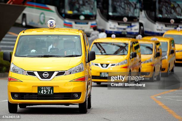 Nissan Motor Co. NV200 Taxi cabs including one for Daiwa Motor Transportation Co., left, drive on a road during a launch event in Tokyo, Japan, on...
