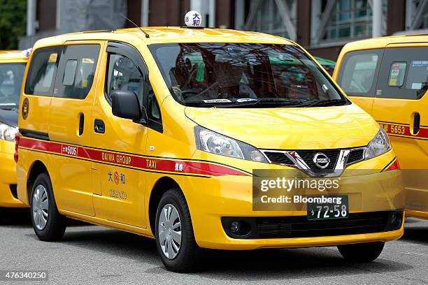 Nissan Motor Co. NV200 Taxi cabs including one for Daiwa Motor Transportation Co., center, sit parked below the Tokyo Tower during a launch event in...