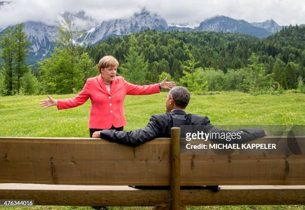 Germany's Chancellor Angela Merkel gestures while chatting with US President Barack Obama sitting on a bench outside the Elmau Castle after a working...