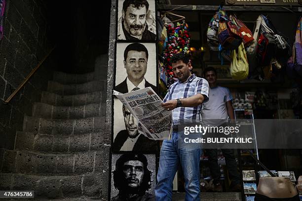 Man reads a newspaper in front of pictures of Selahattin Demirtas , co-chair of the pro-Kurdish People's Democratic Party , Turkish famous singer...