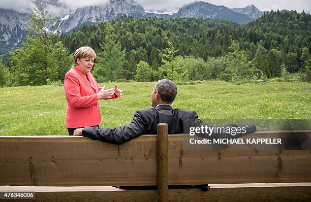 Germany's Chancellor Angela Merkel gestures while chatting with US President Barack Obama sitting on a bench outside the Elmau Castle after a...