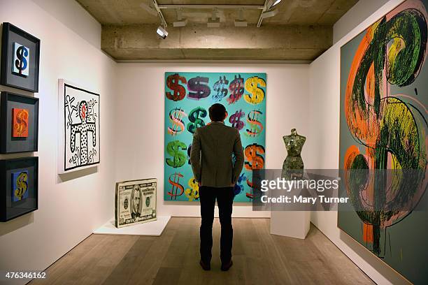 Visitor studies 'Dollar Signs' by Andy Warhol which has an estimated value of £4.5-6.5 million and is going on show at Sotheby's on June 8, 2015 in...