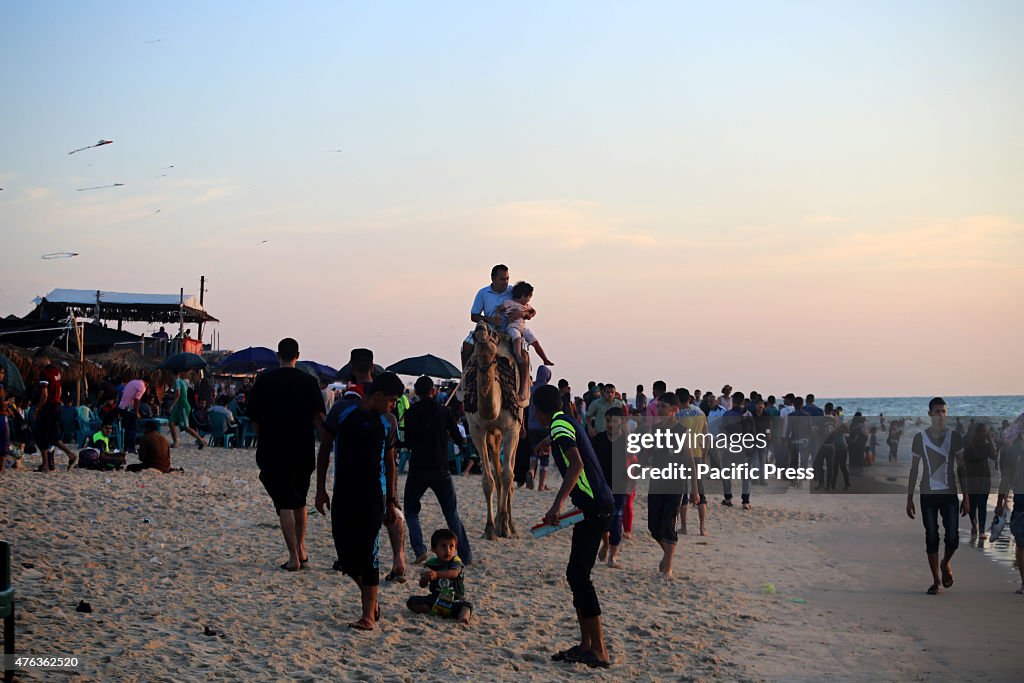 Palestinian man rides a camel along the beach as...