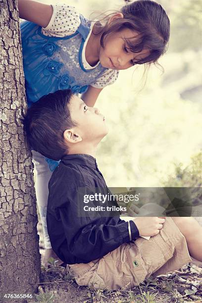 boy studying outdoor his sister looking to him - pakistan family stock pictures, royalty-free photos & images