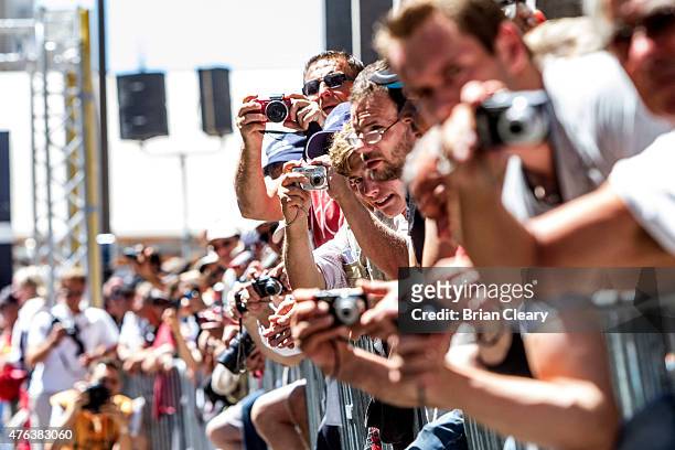 Race fans lean over a fence to photograph race cars during scrutineering before the 24 Hours of Le Mans, on June 8, 2015 in Le Mans, France.