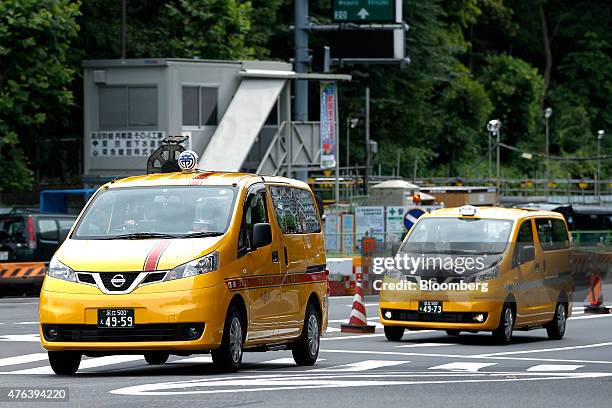 Nissan Motor Co. NV200 Taxi cabs including one for Teito Jidosha Kotsu Co., left, drive on a road during a launch event in Tokyo, Japan, on Monday,...