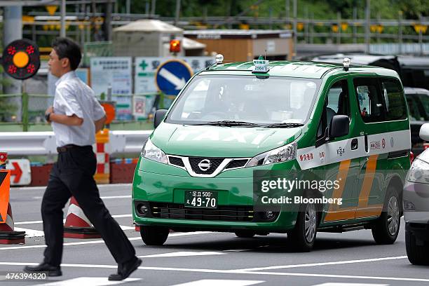 Nissan Motor Co. NV200 Taxi cab for the Tokyo Musen business cooperative stands as a pedestrian crosses the road during a launch event in Tokyo,...