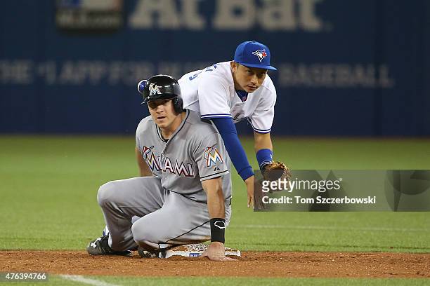Munenori Kawasaki of the Toronto Blue Jays turns a double play in the seventh inning during MLB game action as J.T. Realmuto of the Miami Marlins...