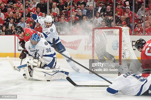 The puck is stopped by goalie Ben Bishop of the Tampa Bay Lightning as Andrew Desjardins of the Chicago Blackhawks and Brian Boyle watch from behind...