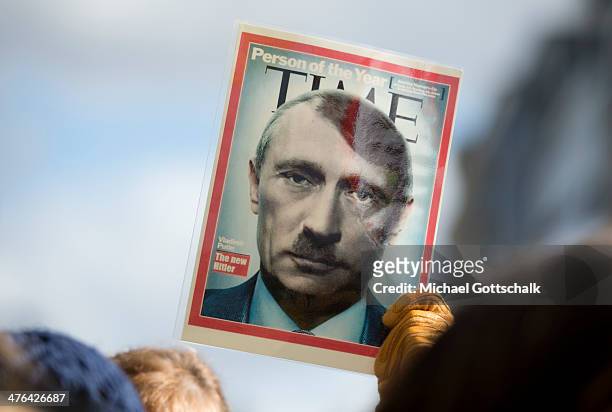 An activist shows a photomontage with Putin and Hitler as part of protest against Russia while foreign ministers take part in a special session of EU...