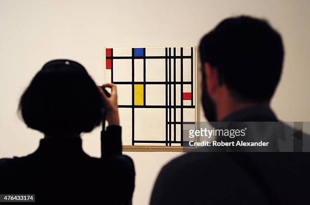Museum of Modern Art visitors look at a painting by Piet Mondrian titled 'Composition in Red, Blue and Yellow,' painted in 1937, on display at the...