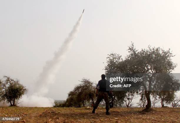 Rebel fighter stands back as a rocket is launched towards a pro-government forces position in the Syrian town of Khan Sheikhun, in Idlib province, on...