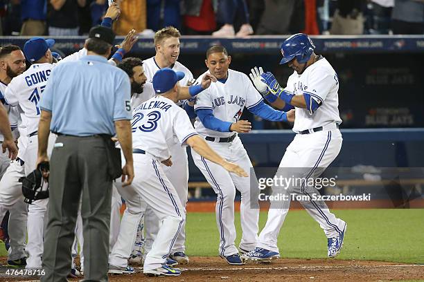 Edwin Encarnacion of the Toronto Blue Jays is congratulated by teammates after hitting a game-winning two-run home run in the ninth inning during MLB...
