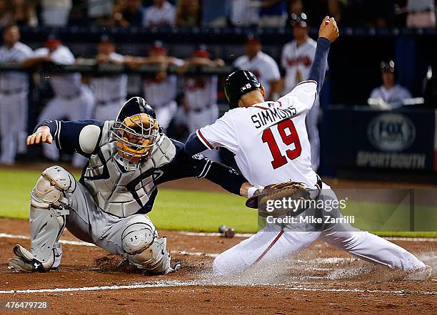 Shortstop Andrelton Simmons of the Atlanta Braves slides behind catcher Derek Norris of the San Diego Padres in the sixth inning to score the tying...