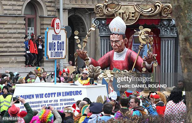 Figure bathes in money reading "live like god in Limburg" during the traditional Rose Monday parade as people celebrate the carnival in Mainz,...