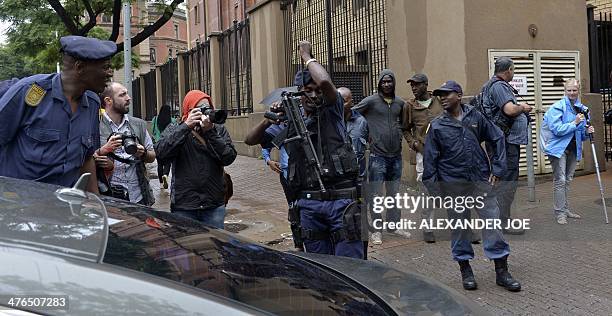 Man takes pictures of an armed policeman in charge of escorting High Court judge Thokozile Matilda Masipa to and from court during the trial of South...