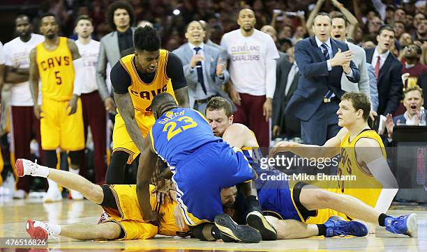 Draymond Green and David Lee of the Golden State Warriors fall on top of Matthew Dellavedova of the Cleveland Cavaliers in the fourth quarter during...