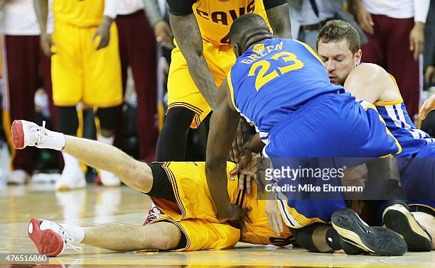 Draymond Green and David Lee of the Golden State Warriors fall on top of Matthew Dellavedova of the Cleveland Cavaliers in the fourth quarter during...
