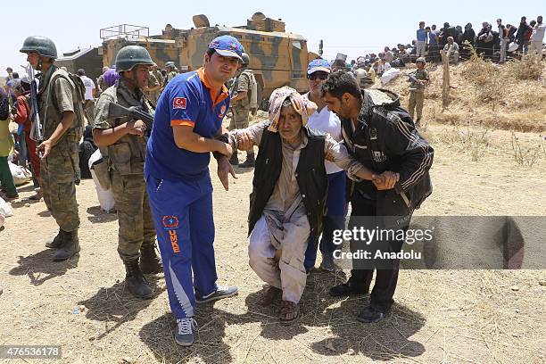 Member of Turkey's National Medical Rescue Team helps a Syrian man after he crossed into Turkey from the borderline in Akcakale district of Sanliurfa...