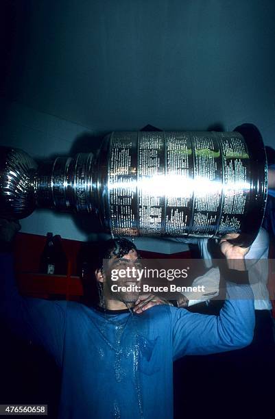 Chris Chelios of the Montreal Canadiens celebrates while holding the Stanley Cup Trophy and having champagne poured over his head in the locker room...