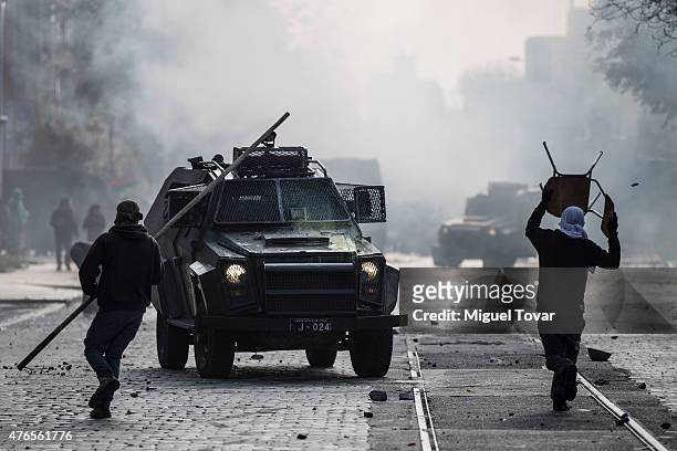 Masked protesters run from teargas thrown by police during a march to protest against the government and police action that injured a fellow student...