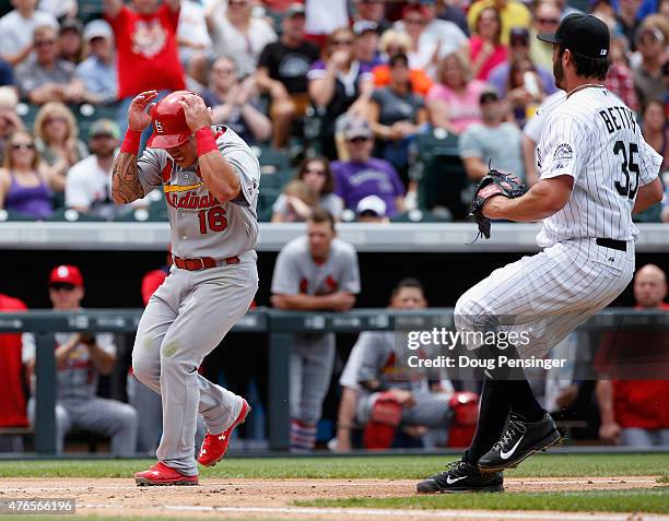 Kolten Wong of the St. Louis Cardinals scores on a wild pitch and protects himself as pitcher Chad Bettis of the Colorado Rockies covers the plate...