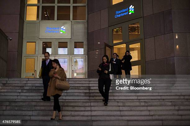 People exit the Standard Chartered Bank building in Central district of Hong Kong, China, on Monday, March 3, 2014. Standard Chartered is scheduled...