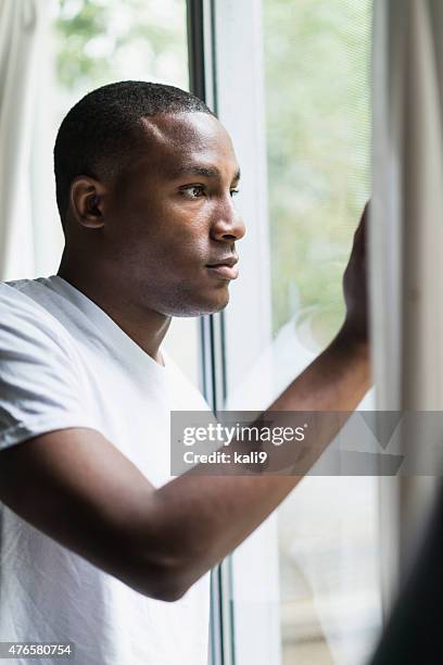 young black man looking out window - african american man depressed bildbanksfoton och bilder