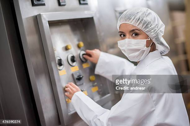 woman operating machine at a food factory - haarnet stockfoto's en -beelden