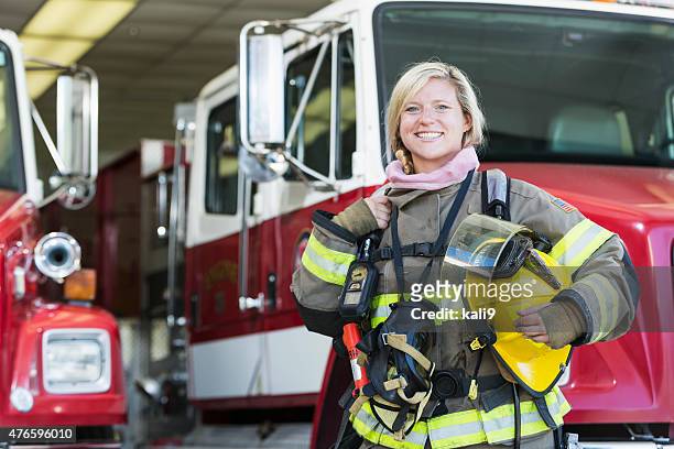 pompiere afro-femminile in piedi davanti al camion dei pompieri - firefighter foto e immagini stock