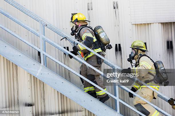 two firefighters in protective gear climbing stairs - fire rescue stock pictures, royalty-free photos & images