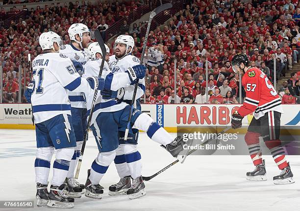 Alex Killorn of the Tampa Bay Lightning celebrates witb teammates as Trevor Van Riemsdyk of the Chicago Blackhawks skates behind, after Killorn...