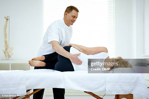 male osteopath treating lower back problem of a woman - lower back stock pictures, royalty-free photos & images