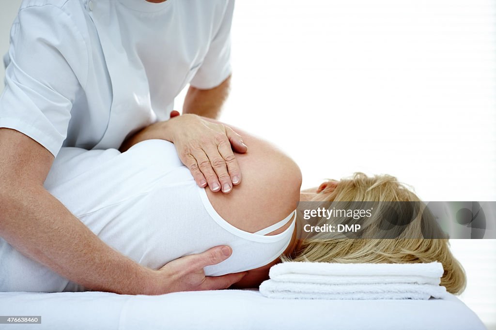 Male osteopath treating back problem of a woman