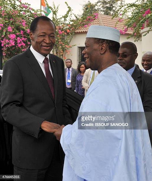 Burkina Faso president Blaise Compaore and Ivory Coast president Alassane Ouattara shake hands on March 4, 2014 at the president's residence in...