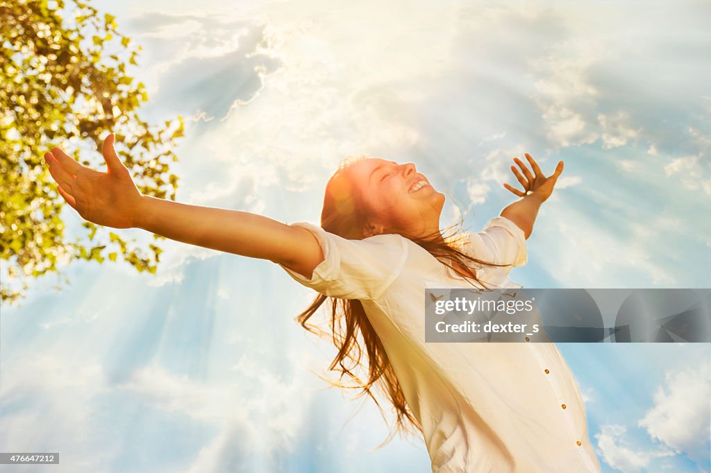 Young woman raising her arms and enjoys sunny day