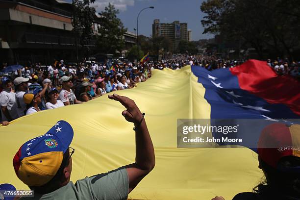 Protesters carry a giant Venezuelan flag while marching in an anti-government demonstration on March 4, 2014 in Caracas, Venezuela. Meanwhile,...