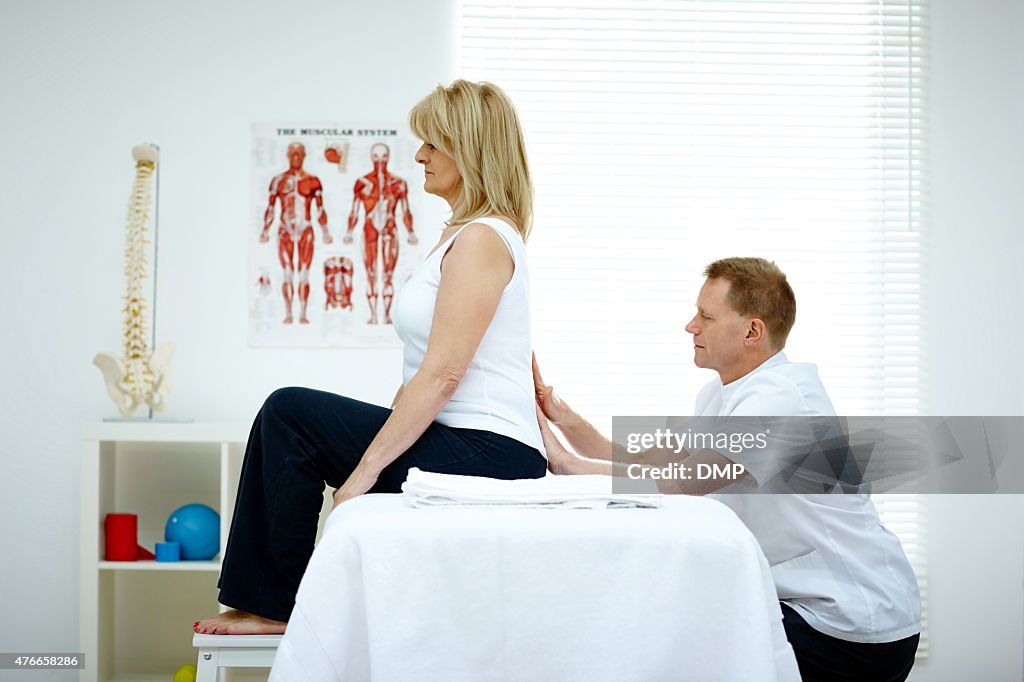 Osteopath treating female patient with back problem