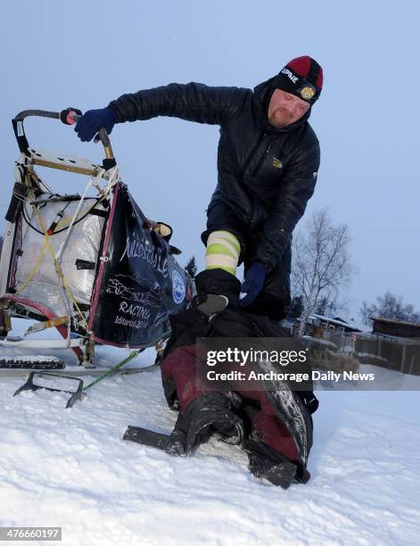 Aaron Burmeister winces with pain as he takes off his bibs at the Nikolai checkpoint during the 2014 Iditarod Trail Sled Dog Race on Tuesday, March 4...