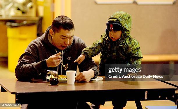 Musher Mike Williams Jr. Has breakfast in the company of two-year-old Karson Alexie in the school cafeteria at the Nikolai checkpoint during the 2014...