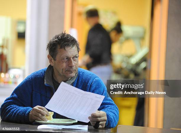 Martin Buser has breakfast and checks the race standings in the school cafeteria at the Nikolai checkpoint during the 2014 Iditarod Trail Sled Dog...