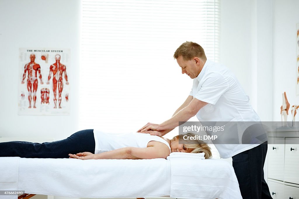 Male osteopath treating back problem of a woman