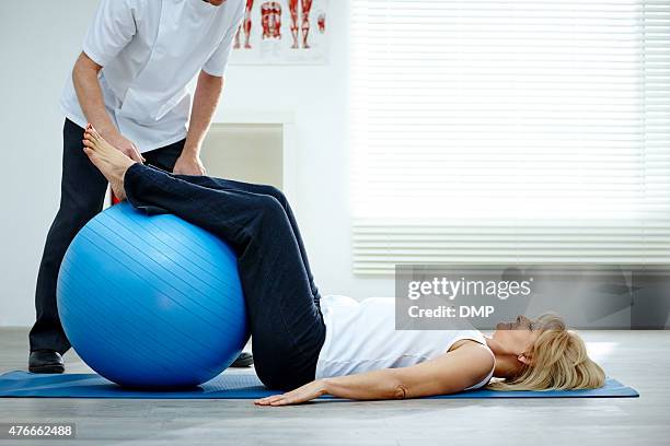 weibliche patienten arbeiten mit körperlichen therapeuten pilates-übung - gymnastikball stock-fotos und bilder