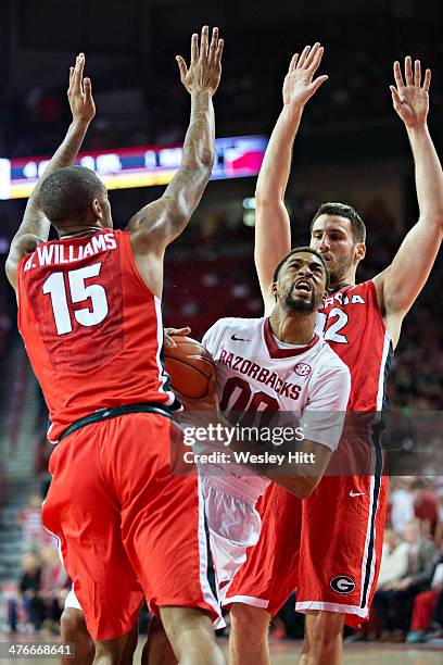 Rashad Madden of the Arkansas Razorbacks drives between Donte Williams and Nemanja Djurisic of the Georgia Bulldogs at Bud Walton Arena on March 1,...