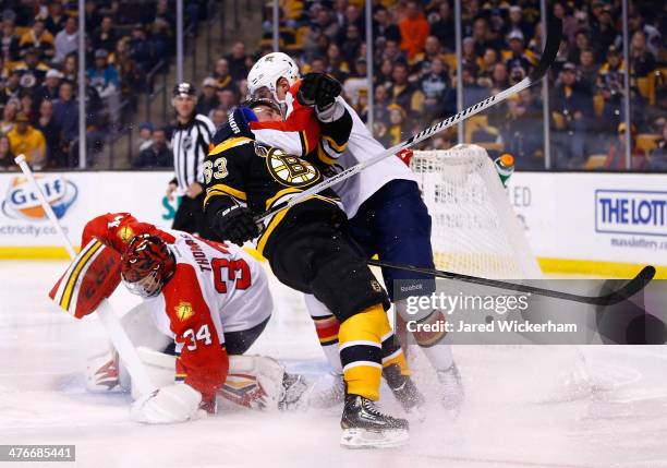 Brad Marchand of the Boston Bruins is hit by Dmitry Kulikov in front of Tim Thomas of the Florida Panthers in the third period during the game at TD...